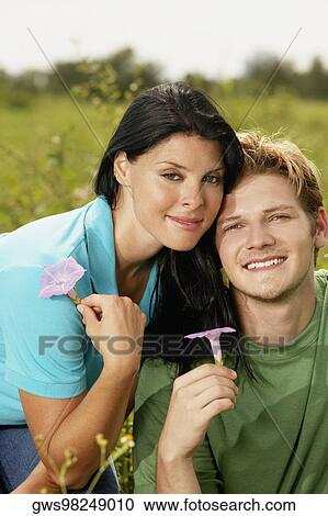 Portrait of a young man and a young woman holding flowers View Large Photo Image Stock Image - Portrait of a young man and a young woman holding flowers. Fotosearch