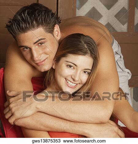 Stock Image - Portrait of a young man embracing a young woman from behind. Fotosearch