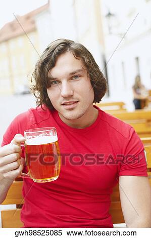 Portrait of a young man holding a glass of beer View Large Photo Image Stock Photography - Portrait of a young man holding a glass of beer . Fotosearch