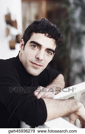 Portrait of a young man leaning against a banister View Large Photo Image Stock Photo - Portrait of a young man leaning against a banister. Fotosearch