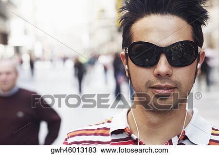 Stock Image - Portrait of a young man listening to an MP3 Player . Fotosearch