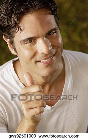 Stock Image - Portrait of a young man showing a thumbs up sign. Fotosearch