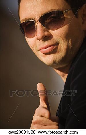 Stock Photo - Portrait of a young man showing a thumbs up sign. Fotosearch