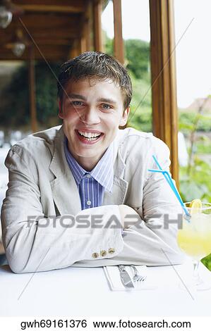 Portrait of a young man sitting in a restaurant View Large Photo Image Stock Photograph - Portrait of a young man sitting in a restaurant . Fotosearch