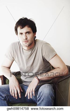 Stock Photo - Portrait of a young man sitting in an armchair. Fotosearch