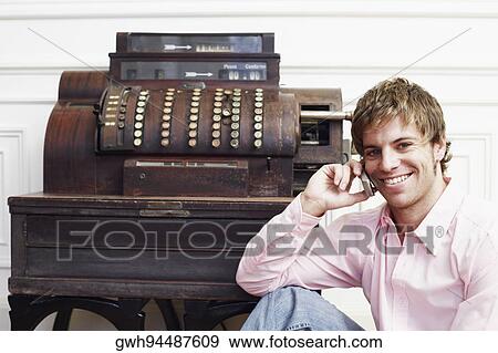 Stock Photo - Portrait of a young man talking on a mobile phone near a typewriter. Fotosearch