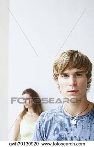 Stock Image - Portrait of a young man with a young woman behind him. Fotosearch