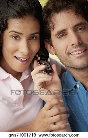 Portrait of a young woman and a mid adult man holding a mobile phone View Large Photo Image Stock Photo - Portrait of a young woman and a mid adult man holding a mobile phone. Fotosearch