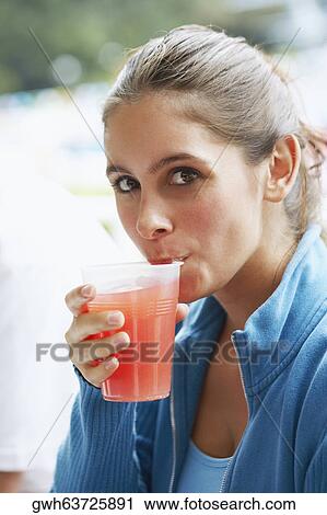 Stock Image - Portrait of a young woman drinking a glass of juice. Fotosearch