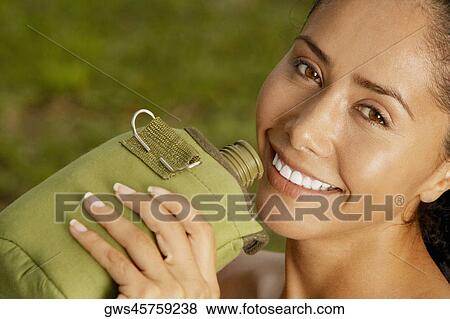 Stock Photo - Portrait of a young woman drinking from a bottle. Fotosearch