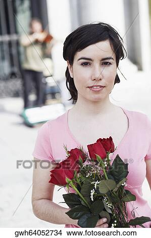 Portrait of a young woman holding a bunch of roses View Large Photo Image Picture - Portrait of a young woman holding a bunch of roses . Fotosearch