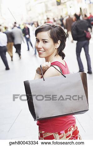 Portrait of a young woman holding a shopping bag View Large Photo Image Picture - Portrait of a young woman holding a shopping bag . Fotosearch