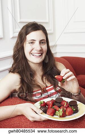 Portrait of a young woman holding a plate of strawberries with chocolates and smiling View Large Photo Image Picture - Portrait of a young woman holding a plate of strawberries with chocolates and smiling. Fotosearch