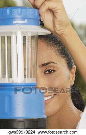 Portrait of a young woman holding a lantern in front of her face View Large Photo Image Picture - Portrait of a young woman holding a lantern in front of her face. Fotosearch
