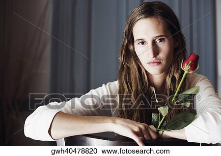 Portrait of a young woman holding a rose View Large Photo Image Stock Image - Portrait of a young woman holding a rose. Fotosearch