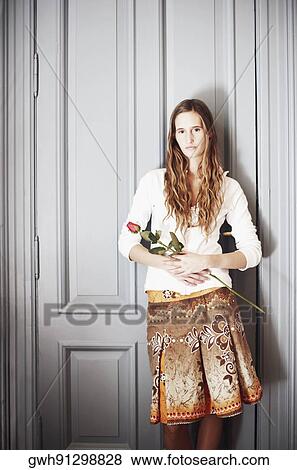 Portrait of a young woman holding a rose View Large Photo Image Stock Photo - Portrait of a young woman holding a rose. Fotosearch