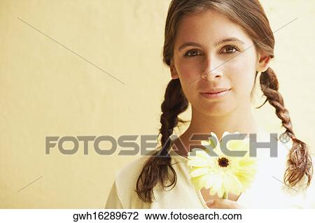 Portrait of a young woman holding a daisy flower View Large Photo Image Stock Image - Portrait of a young woman holding a daisy flower. Fotosearch