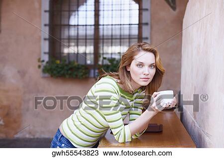 Stock Image - Portrait of a young woman holding a coffee cup. Fotosearch