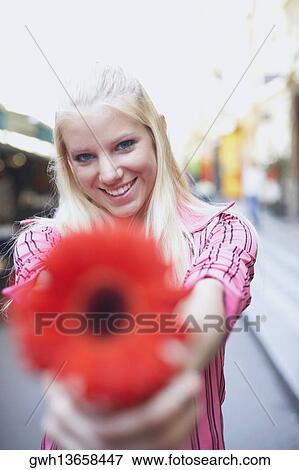 Stock Photo - Portrait of a young woman holding a flower. Fotosearch