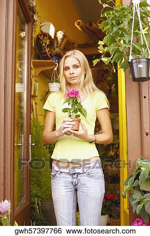 Portrait of a young woman holding a potted plant View Large Photo Image Stock Photograph - Portrait of a young woman holding a potted plant . Fotosearch