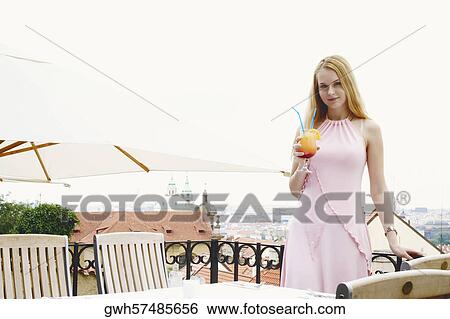 Stock Photograph - Portrait of a young woman holding a drink . Fotosearch