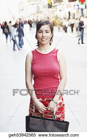 Stock Photography - Portrait of a young woman holding a shopping bag . Fotosearch