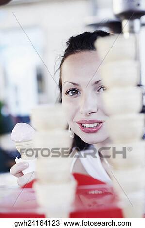 Stock Image - Portrait of a young woman holding an ice-cream cone . Fotosearch