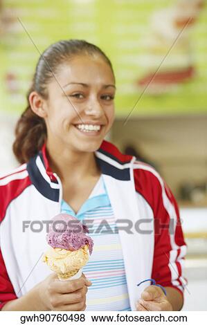Portrait of a young woman holding an ice-cream and smiling View Large Photo Image Stock Photo - Portrait of a young woman holding an ice-cream and smiling. Fotosearch