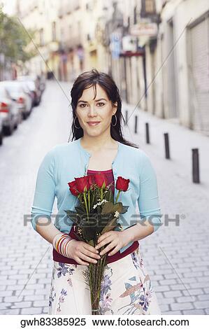 Portrait of a young woman holding bouquet of flowers and smiling View Large Photo Image Stock Photography - Portrait of a young woman holding bouquet of flowers and smiling . Fotosearch