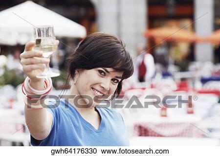 Portrait of a young woman holding up a glass of white wine View Large Photo Image Stock Image - Portrait of a young woman holding up a glass of white wine . Fotosearch