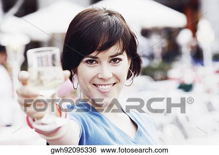 Portrait of a young woman holding up a glass of white wine View Large Photo Image Stock Photograph - Portrait of a young woman holding up a glass of white wine . Fotosearch