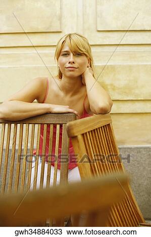 Portrait of a young woman leaning against a chair View Large Photo Image Stock Image - Portrait of a young woman leaning against a chair. Fotosearch
