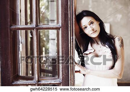 Stock Photography - Portrait of a young woman leaning against a door. Fotosearch