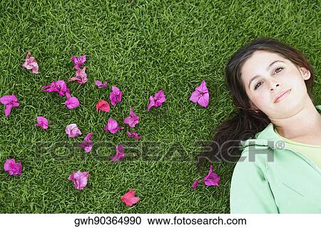 Portrait of a young woman lying on the grass View Large Photo Image Stock Image - Portrait of a young woman lying on the grass. Fotosearch