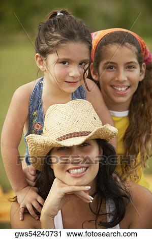 Stock Image - Portrait of a young woman posing with her two daughters with her hand on her chin. Fotosearch