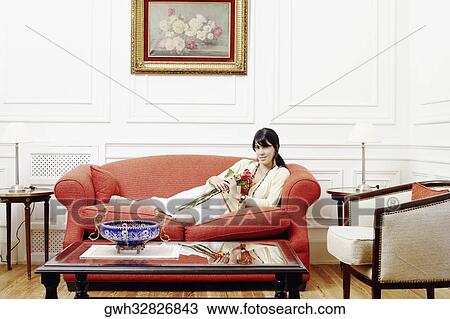 Portrait of a young woman reclining on a couch and holding a bunch of flowers View Large Photo Image Stock Image - Portrait of a young woman reclining on a couch and holding a bunch of flowers. Fotosearch