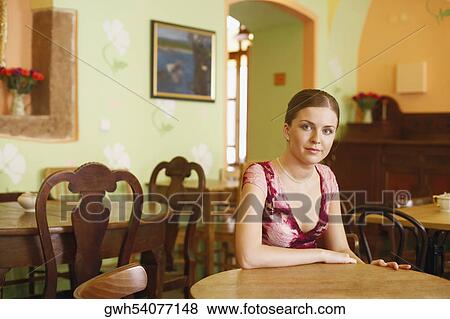 Stock Photo - Portrait of a young woman sitting at a table . Fotosearch