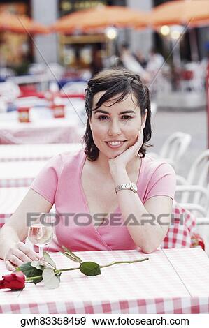 Portrait of a young woman sitting at a table in a sidewalk cafe View Large Photo Image Stock Photo - Portrait of a young woman sitting at a table in a sidewalk cafe . Fotosearch