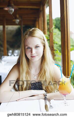 Picture - Portrait of a young woman sitting in a restaurant . Fotosearch
