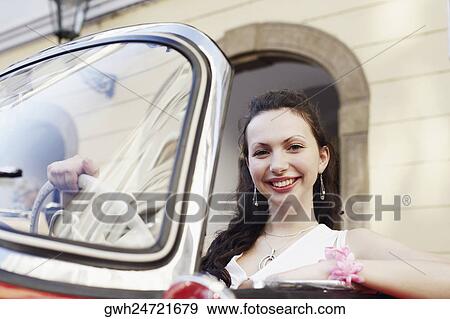 Stock Photo - Portrait of a young woman sitting in a car and smiling . Fotosearch