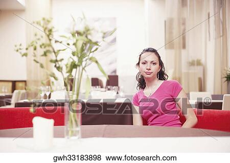 Portrait of a young woman sitting in a restaurant View Large Photo Image Stock Photo - Portrait of a young woman sitting in a restaurant . Fotosearch