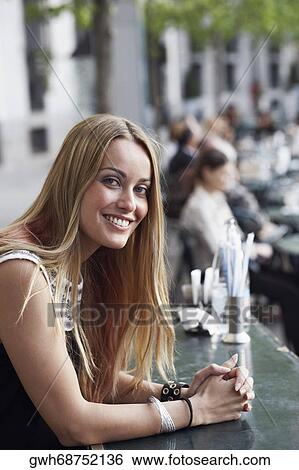 Portrait of a young woman sitting in a sidewalk cafe View Large Photo Image Stock Photograph - Portrait of a young woman sitting in a sidewalk cafe . Fotosearch
