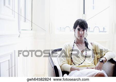 Portrait of a young woman sitting in an armchair View Large Photo Image Picture - Portrait of a young woman sitting in an armchair. Fotosearch