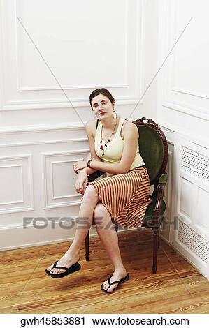 Portrait of a young woman sitting in an armchair at the corner of a room View Large Photo Image Stock Image - Portrait of a young woman sitting in an armchair at the corner of a room. Fotosearch