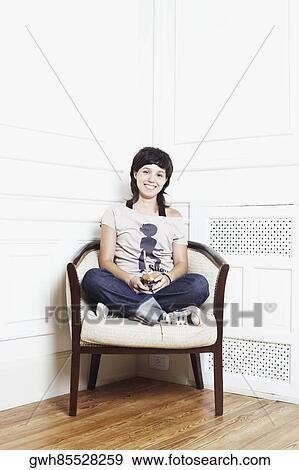 Stock Photo - Portrait of a young woman sitting in an armchair and smiling. Fotosearch