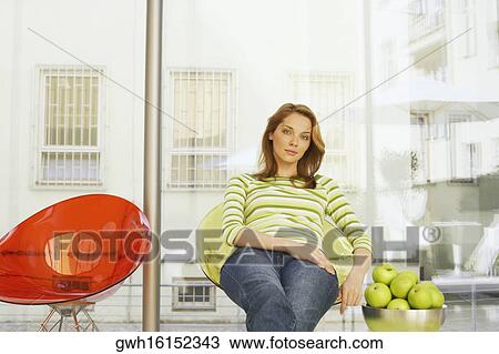 Stock Image - Portrait of a young woman sitting on a chair. Fotosearch