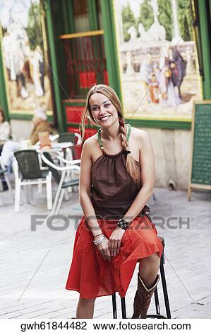 Portrait of a young woman sitting on a stool and smiling View Large Photo Image Stock Image - Portrait of a young woman sitting on a stool and smiling . Fotosearch