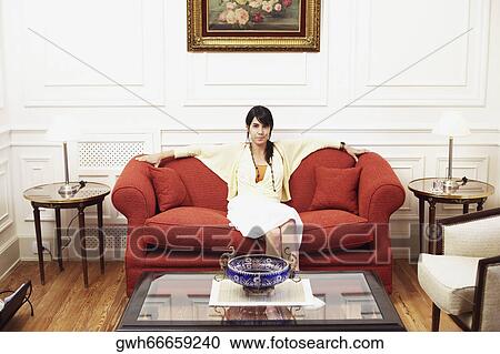 Portrait of a young woman sitting on a couch View Large Photo Image Stock Image - Portrait of a young woman sitting on a couch. Fotosearch