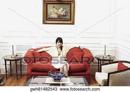 Portrait of a young woman sitting on a couch View Large Photo Image Stock Image - Portrait of a young woman sitting on a couch. Fotosearch