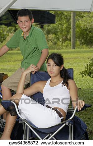 Portrait of a young woman sitting on a folding chair and holding a teenage boys hand View Large Photo Image Stock Image - Portrait of a young woman sitting on a folding chair and holding a teenage boys hand. Fotosearch
